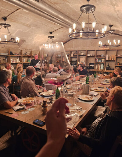 bild von einem weinglas in einem berner gewölbekeller. im hintergrund personen die gemeinsam ein wine & dine geniessen.