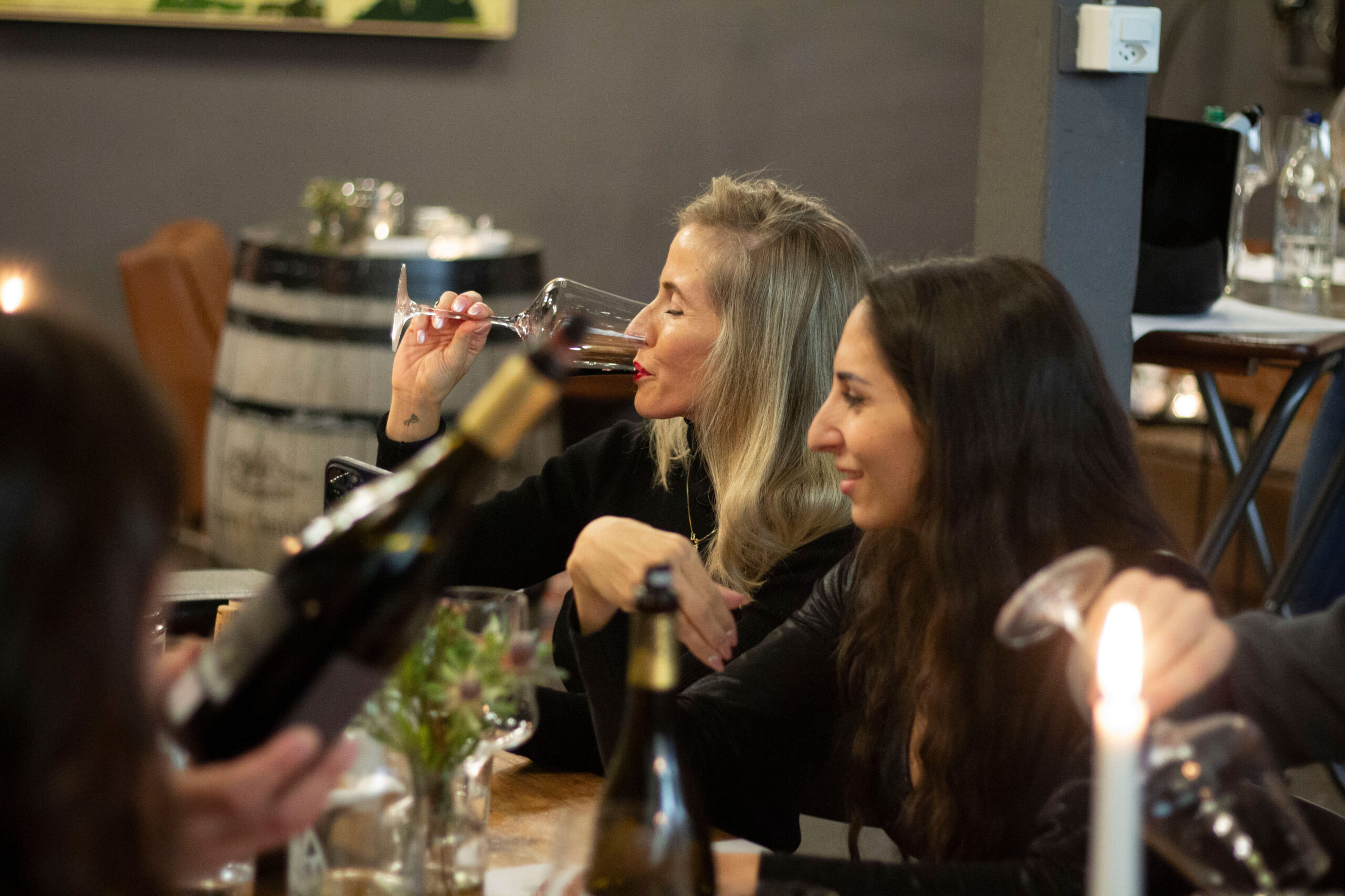 Mehrere Personen auf dem Bild, die Wein trinken und miteinander reden und interagieren.