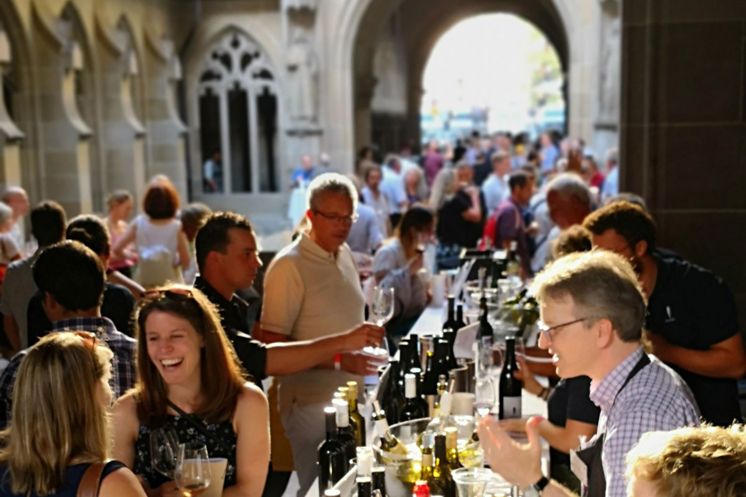 Eventimpression vom letzter Zürcher Weine going Downtown. Mehrere Winzer im Kreuzgang des Fraumünster, die die Besucher beraten, ihnen Wein einschenken und Freude vermitteln.